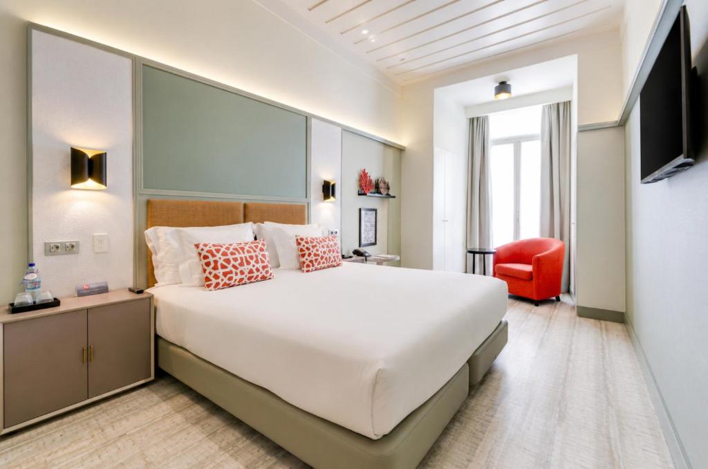 a bedroom with a large white bed and a red chair at Vincci Baixa in Lisbon
