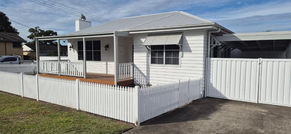 a white house with a fence in front of it at Elegant White Cottage in Bomaderry