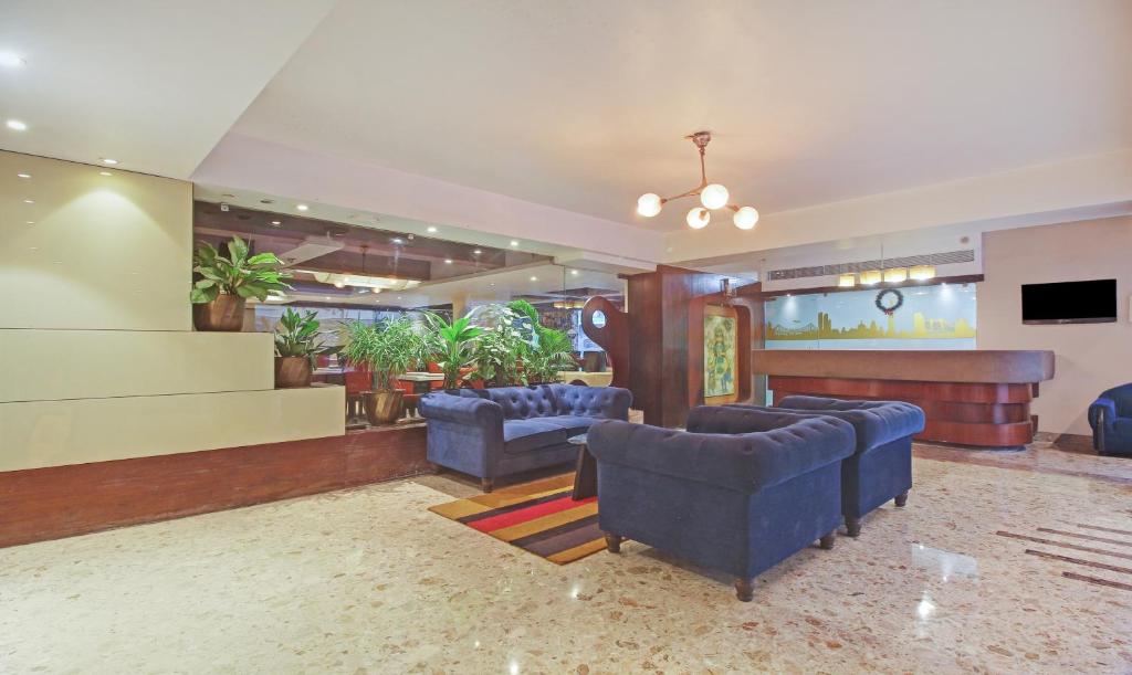a lobby with blue chairs and a flat screen tv at Dee Empresa Hotel in Kolkata