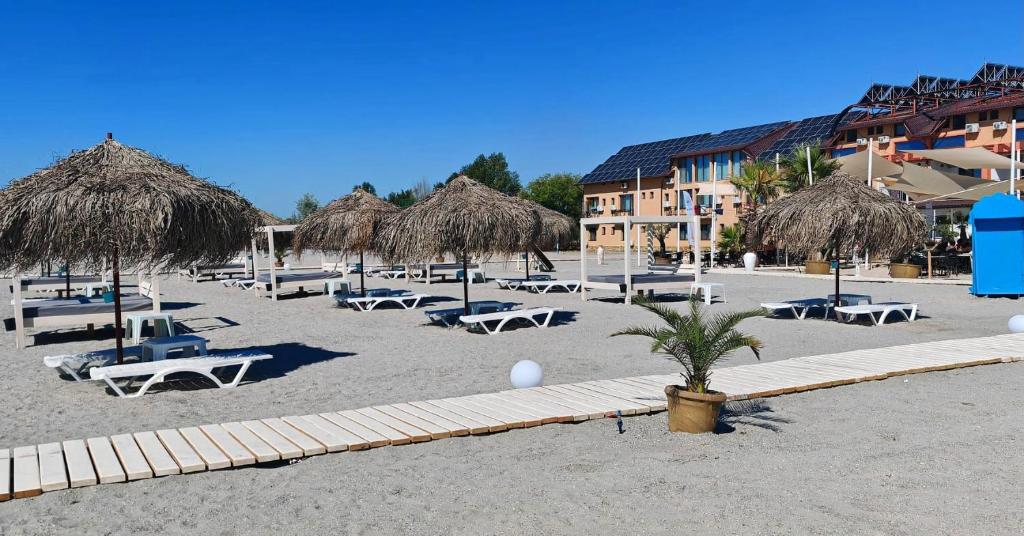 a beach with chairs and straw umbrellas and tables at Complex Turistic Perla Venusului in Venus