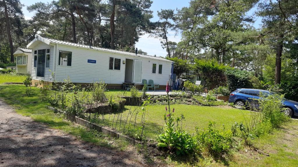 a white house with a car parked in front of it at Luiwagen in Raalte