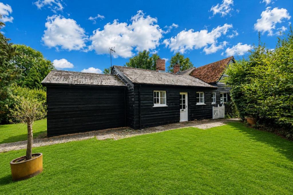 a black house with a green yard at The Cottage at Cobbolds Mill in Monks Eleigh