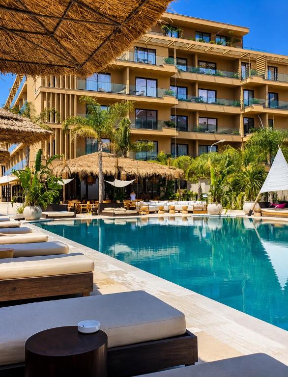a swimming pool with chaise lounges and a hotel at Palmera Escape Radhime in Vlorë