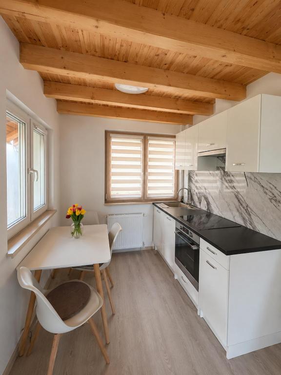 a kitchen with white cabinets and a table and chairs at Pop Apartment Kerepes in Kerepes