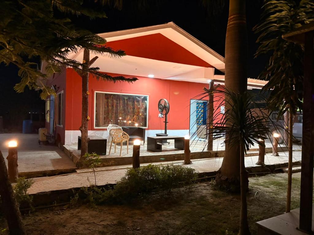 a small house with a red wall at night at TAG Farm in Greater Noida