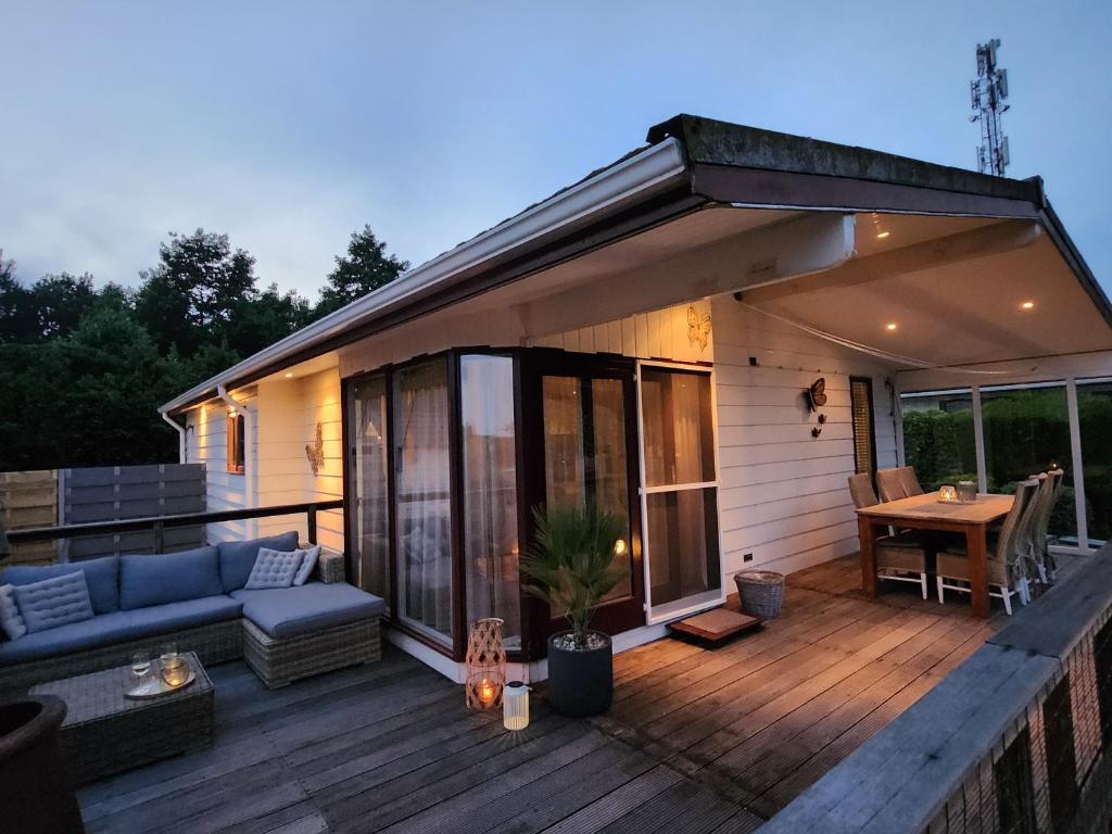 a house with a deck with a couch and a table at Cozy Chalet in Berkhout