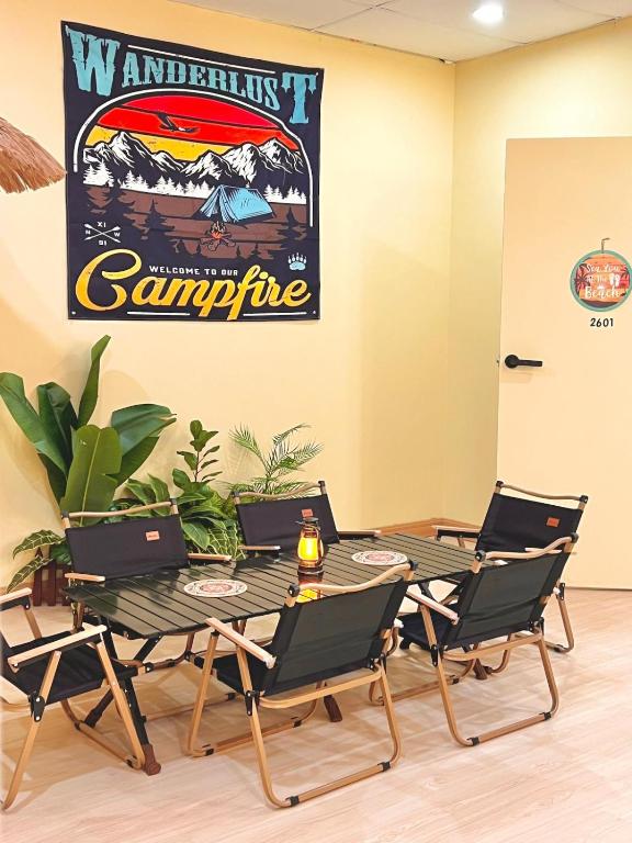 a table and chairs in a room with a poster on the wall at Camp Fire Homestay 2601 in Mersing