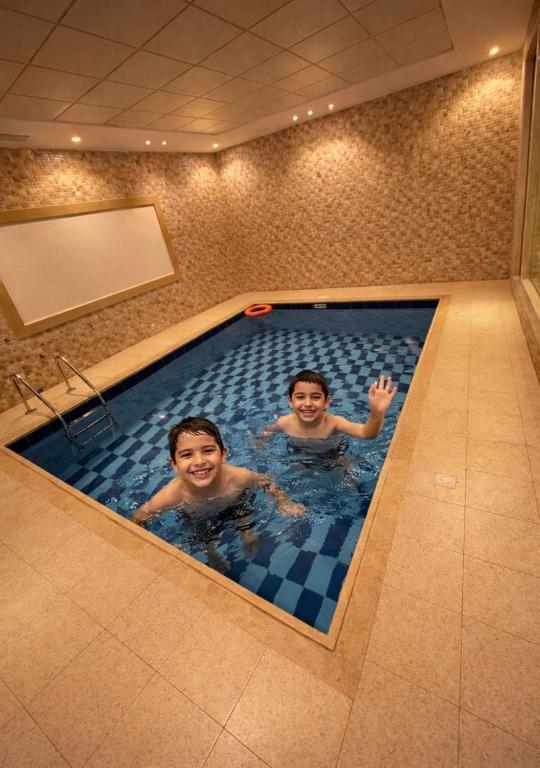 two boys are swimming in a swimming pool at شاليهات حديقة الوسام لبيوت العطلات 1 in Taif