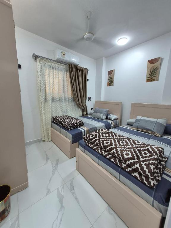 a bedroom with two beds and a window at Ali Guest House in Jazīrat al ‘Awwāmīyah