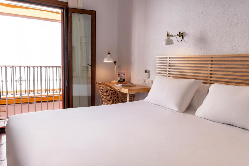a bedroom with a large white bed and a balcony at Sercotel Puerto de Santa María in El Puerto de Santa María