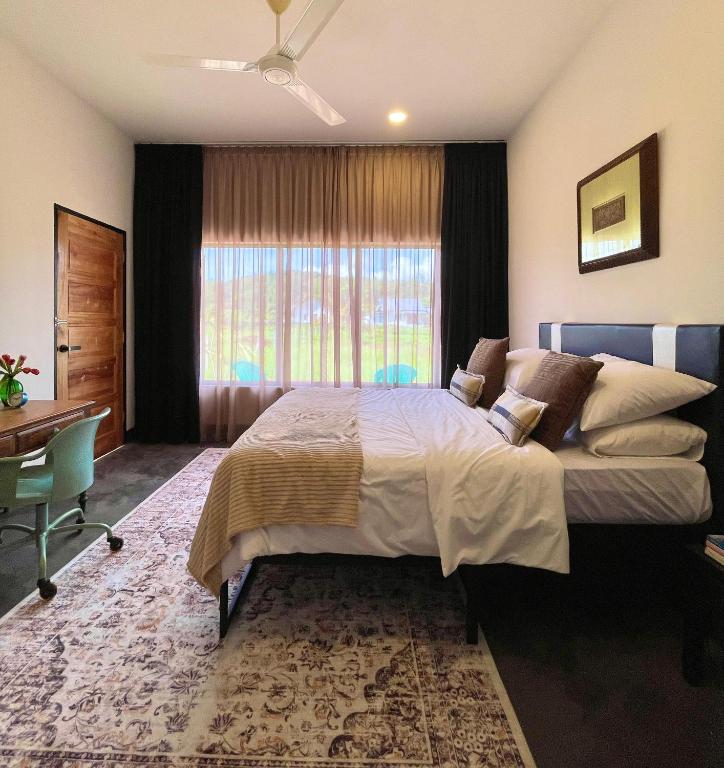 a bedroom with a bed and a desk and a window at Rumah Cermin in Langkawi Intl