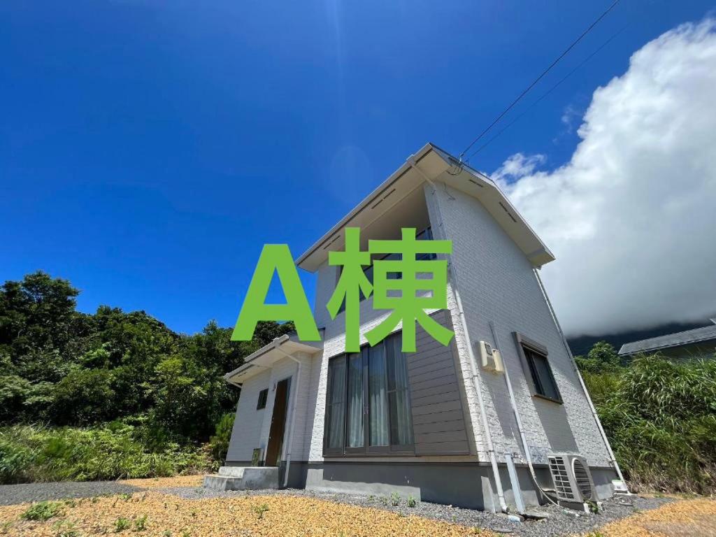a small house with a green sign on it at ココナッツ屋久島 in Yakushima