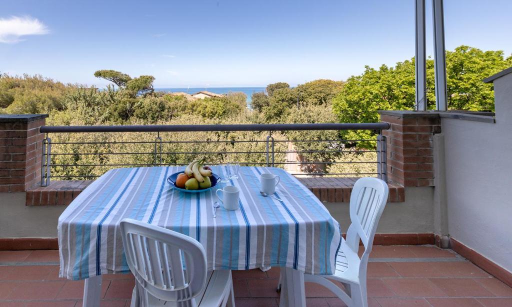 a table with a bowl of fruit on a balcony at Villa La Cavaliera in San Vincenzo
