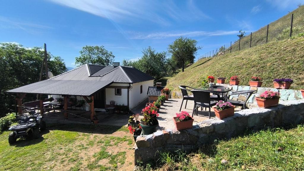 a cottage with a table and chairs and flowers at Vujanac vikend kuća in Raška