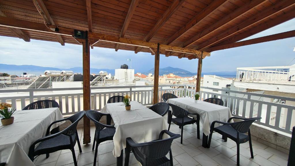 a patio with white tables and chairs on a balcony at Achilleion-Edipsos in Loutra Edipsou