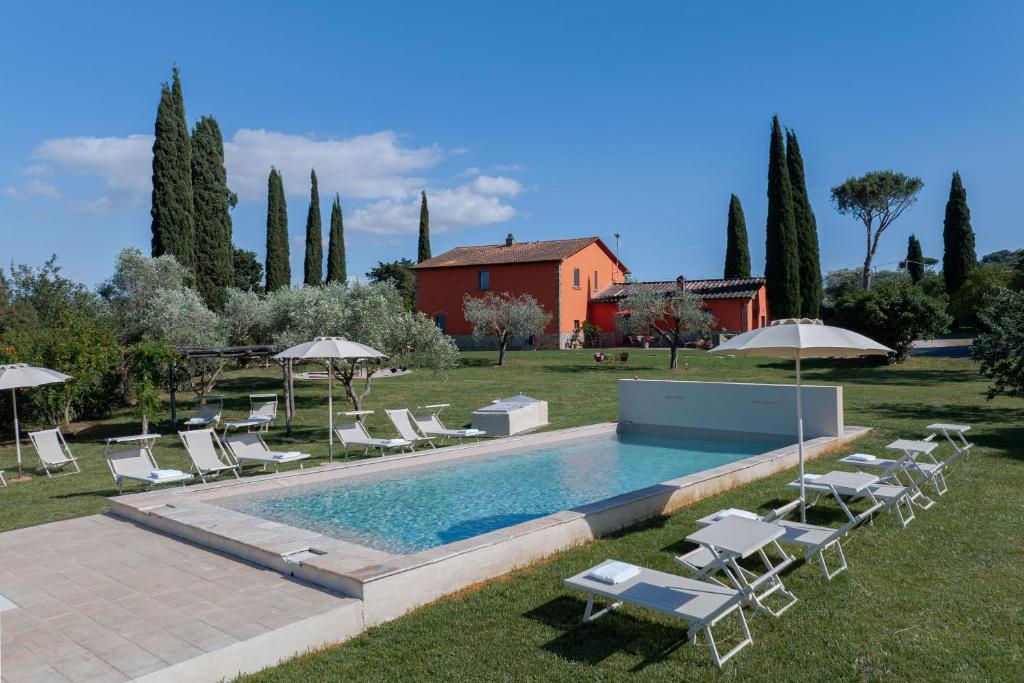 a pool with chairs and umbrellas next to a house at Zuccherini in Buriano