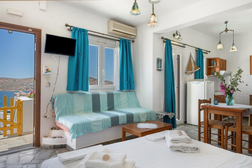 a room with two beds and a window with blue curtains at Agnadi Studio in Serifos Chora