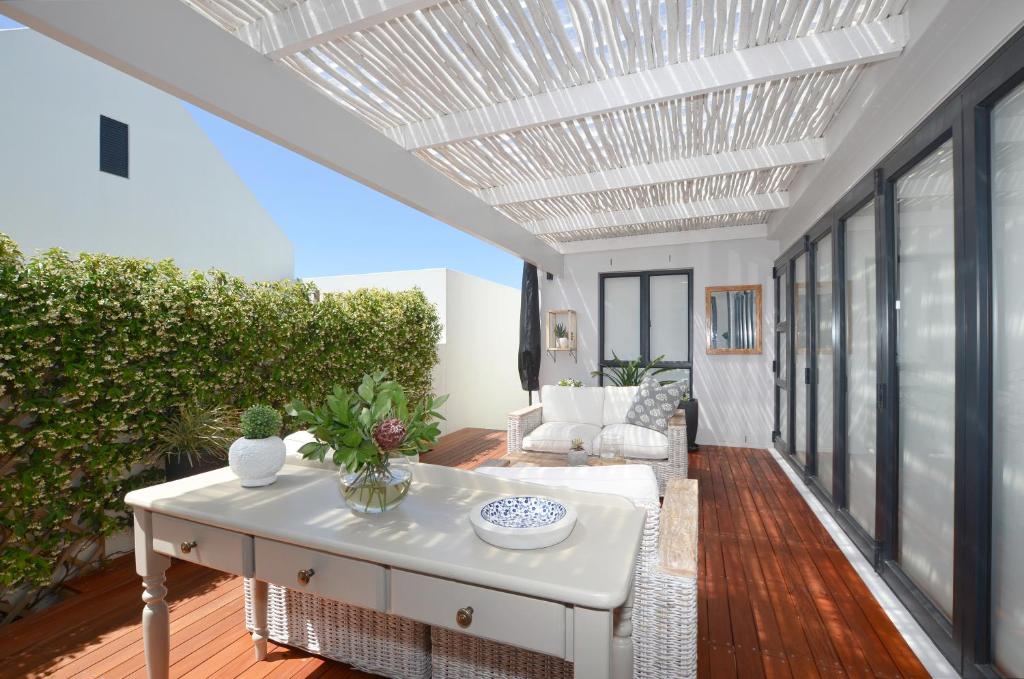 a patio with a white table and a white couch at Caracal 54 Overnight for 2 in Yzerfontein