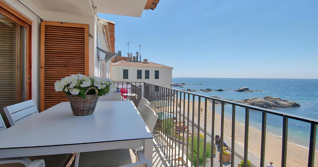 a balcony with a table with a vase of flowers at Exclusive Position Front Line Apartments Calau in Calella de Palafrugell