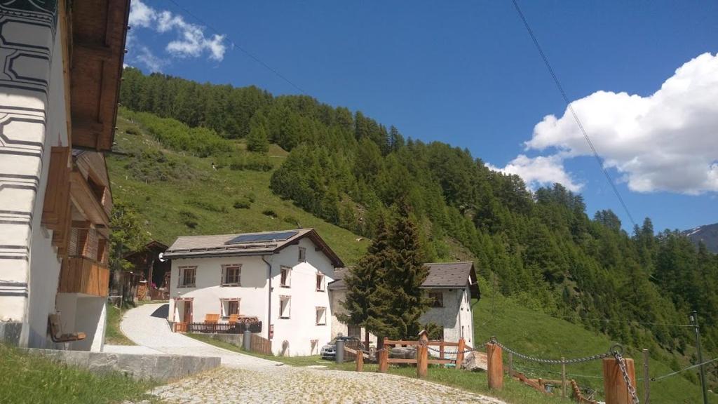 ein kleines weißes Haus auf einem Hügel mit einem Berg in der Unterkunft Berghaus am Sonnenhang Valpaschun in Valchava