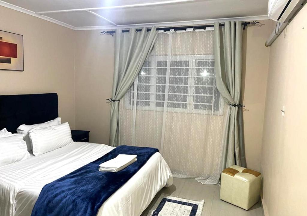 a bedroom with a bed and a window at Sofies's Apartments in Lusaka