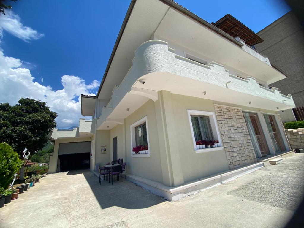 a white house with two windows and a patio at Guest House Nuhellari - Family stay & Breakfast near Osumi Canyons in Çorovodë