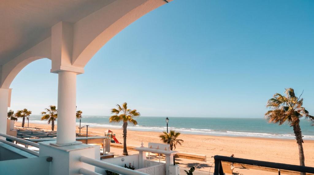 a view of the beach from the balcony of a beach house at Hotel Vértice Chipiona Mar in Chipiona