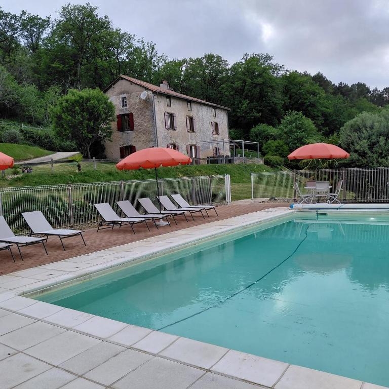 a swimming pool with chairs and umbrellas and a building at B&B Angueur in Montrem