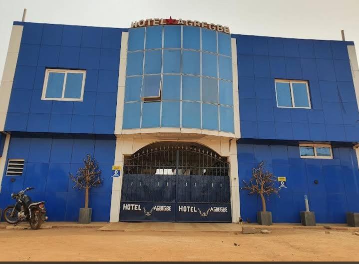 a blue building with a motorcycle parked in front of it at Hôtel Agbégbé in Abomey