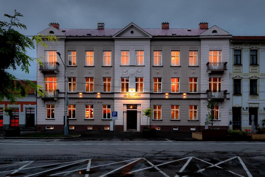 ein großes weißes Gebäude mit orange beleuchteten Fenstern in der Unterkunft BELROS Hotel in Trenčín
