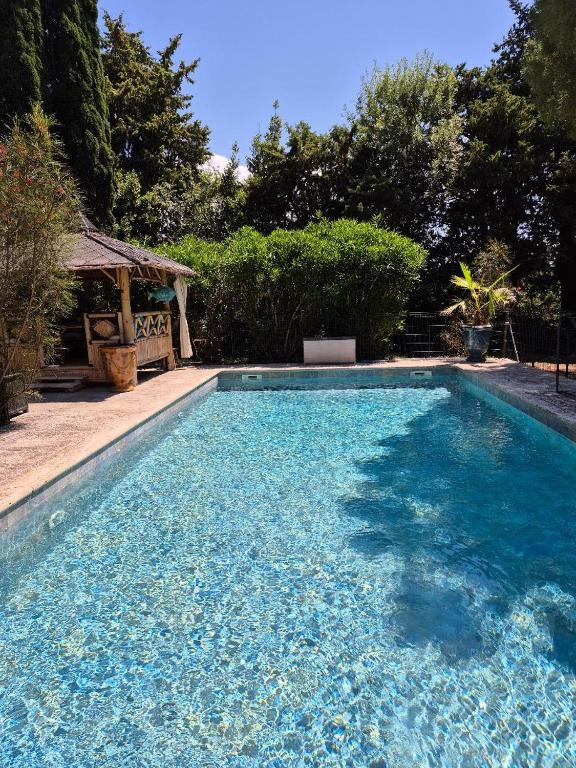 a swimming pool with blue water in a yard at Partie de ferme appartement in Paluds de Noves