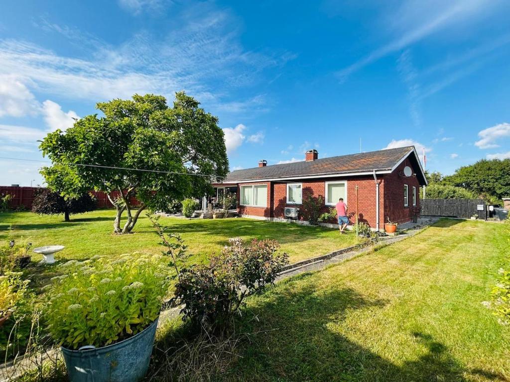a house with a person standing in the yard at Cozy Home - Holiday, Sleepover in Rødbyhavn