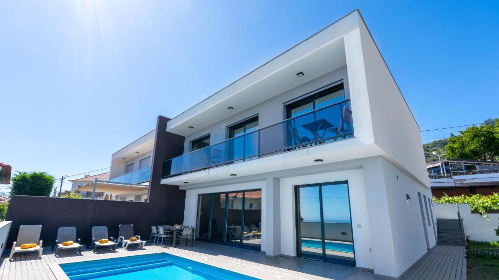 a large white house with a swimming pool at Evoque Villa by LovelyStay in Arco da Calheta