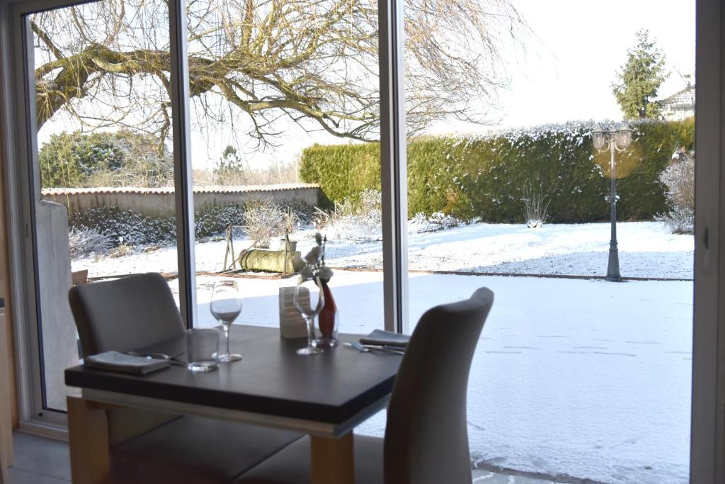 una mesa con 2 copas de vino y vistas a un patio cubierto de nieve en Logis Restaurant & Hôtel À la 12, en Delme