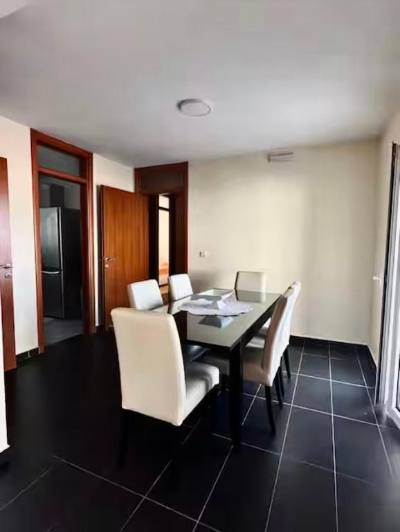 a dining room with a black table and white chairs at Cozy&Spacious in Kotor