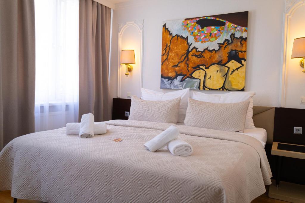 a bedroom with a large white bed with towels on it at Hotel Attaché in Vienna