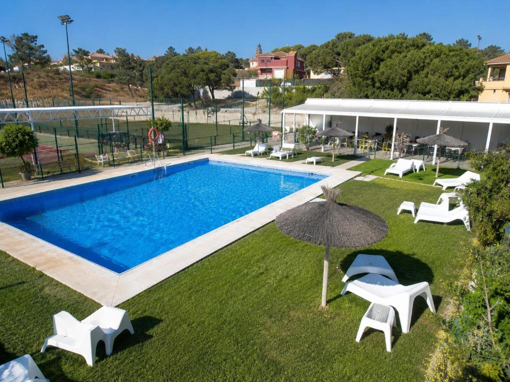 a swimming pool with white chairs and an umbrella at YOKOI La Antilla in La Antilla