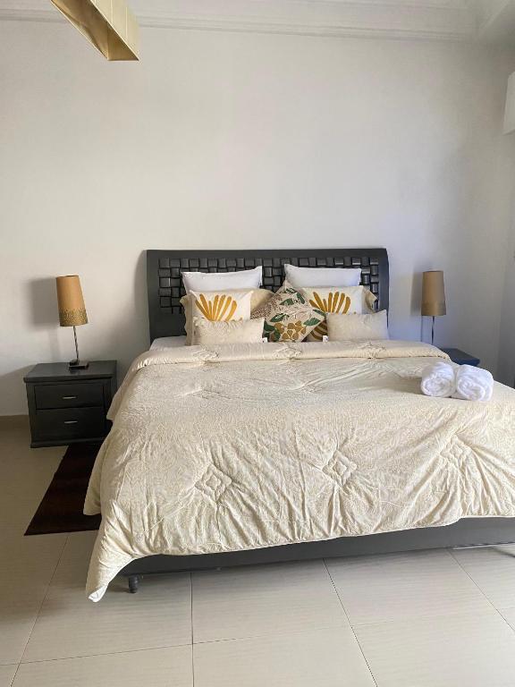 a bedroom with a large bed with white sheets and pillows at Immeuble Mohamet Mbacké TAÏF in Dakar