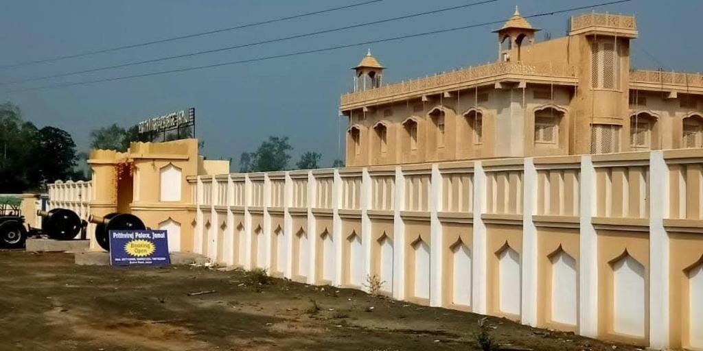 a white fence next to a large building at Prithviraj palace in Shahdol