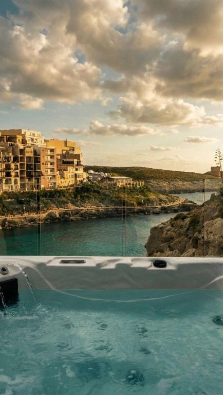 Blick auf ein Gewässer mit Gebäuden in der Unterkunft Water's Edge Suite Xlendi Direct Seafront with Private Roof Top Jacuzzi in Munxar