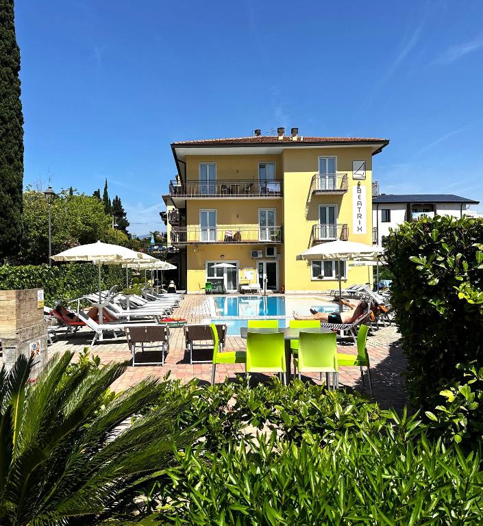 ein Hotel mit Tisch und Stühlen und einem Pool in der Unterkunft Residence Beatrix in Bardolino