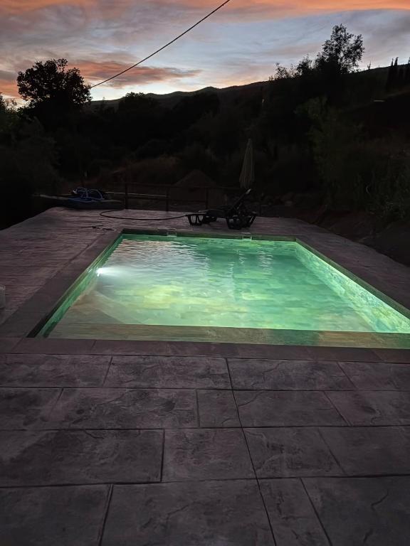 a swimming pool with a sunset in the background at Alpujarra Las Lindes in Pórtugos