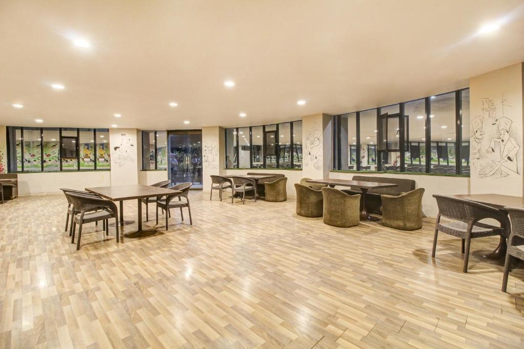 a dining room with tables and chairs and windows at Hotel O New Pride in Sāngli