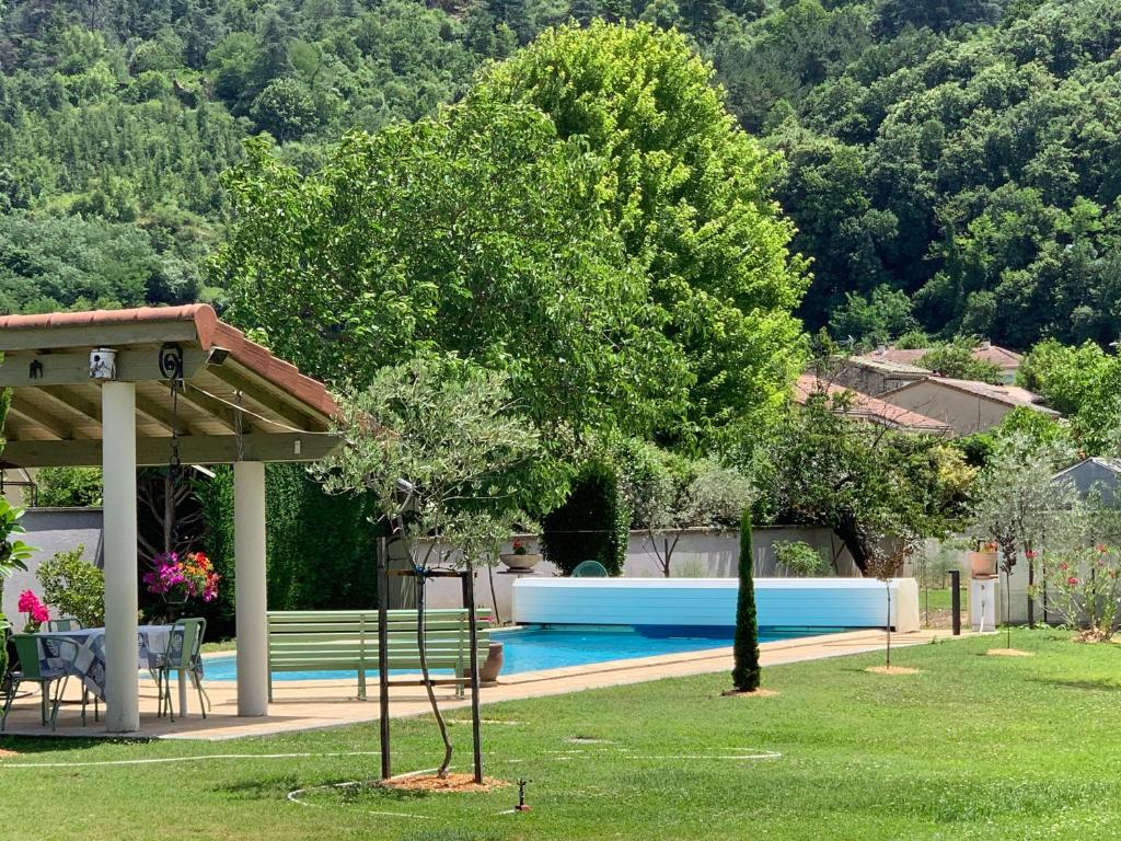 a yard with a swimming pool and a tree at Escapade Vallée du Doux in Tournon-sur-Rhône