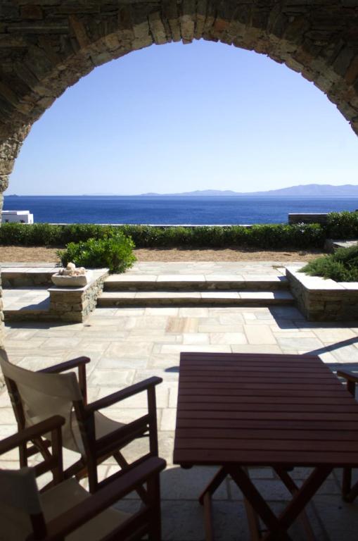 an archway with chairs and a bench and the ocean at Rosalie Home - Aegean Deck in Tinos