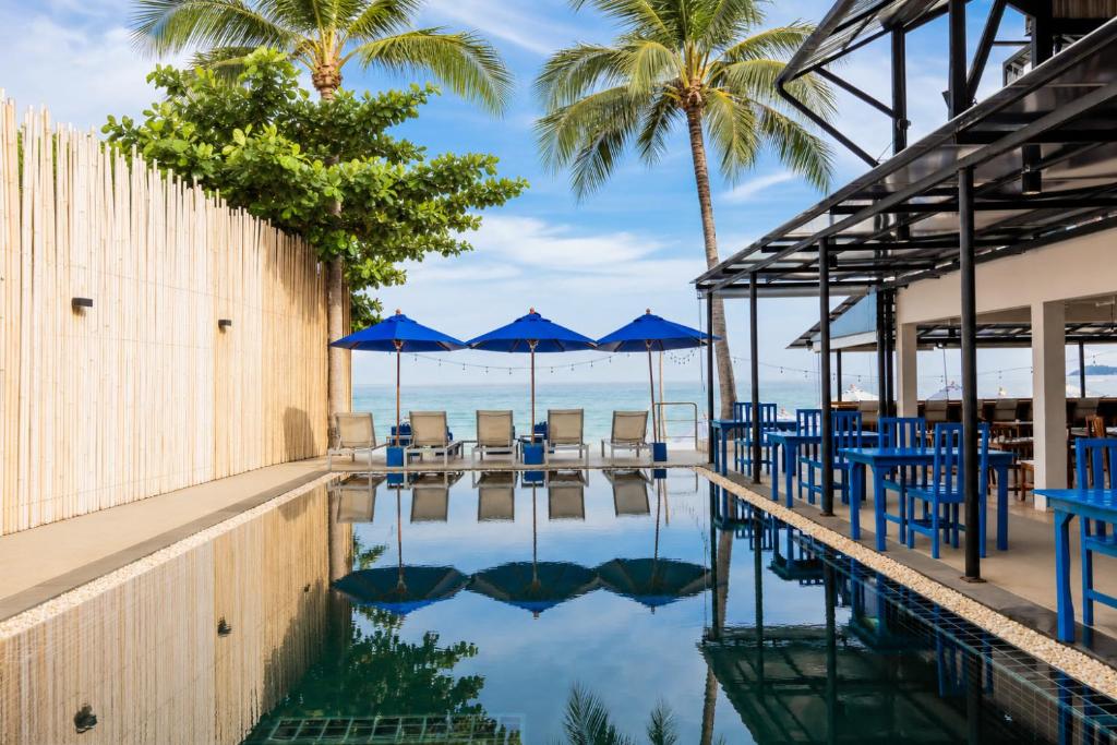 a swimming pool with blue chairs and umbrellas at Malibu Beach Resort Samui in Chaweng