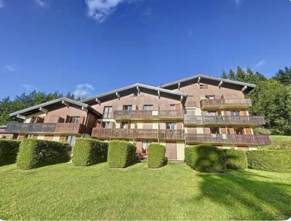 a large building with balconies on a green lawn at Studio montagne Les Carroz in Arâches-la-Frasse