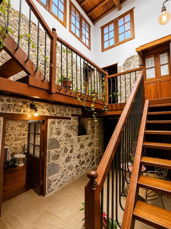 a wooden staircase in a house with a stone wall at Casa Luna - Agüimes in Agüimes