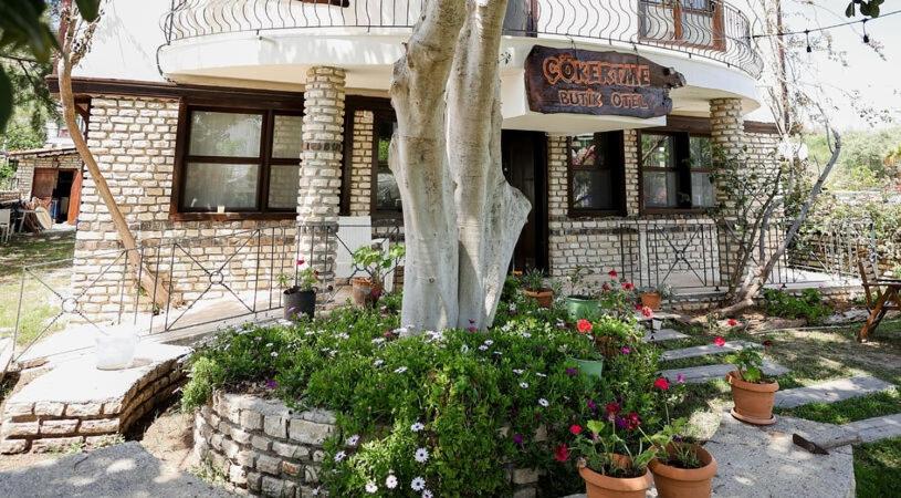 a house with a tree and flowers in front of it at Çökertme Butik Otel in Çökertme