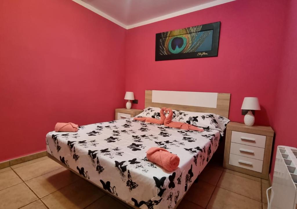 a bedroom with a bed and a pink wall at Areatza Home Mountain in Santiago de la Espada
